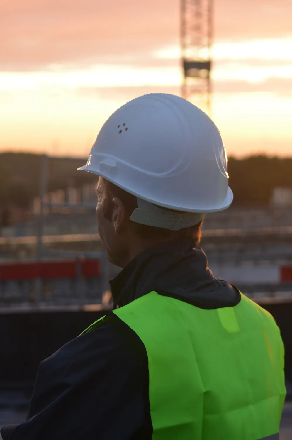 Herzog Kuntscher – Baukonzept Unternehmergesellschaft – Dieses Bild fängt einen Moment ein, in dem ein Bauarbeiter eine Projektbaustelle überwacht.